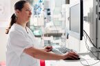 Eine Pflegefachfrau steht im Skills Lab und schaut etwas im Computer nach
