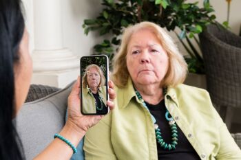 A person takes a photo of an elderly woman with a smartphone