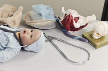 Auf einem Tisch liegt eine Babypuppe sowie verschiedene Modelle und Hilfsmittel