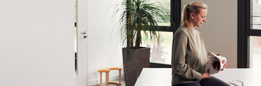 Eine Frau betrachtet ein anatomisches Modell eines Beckens