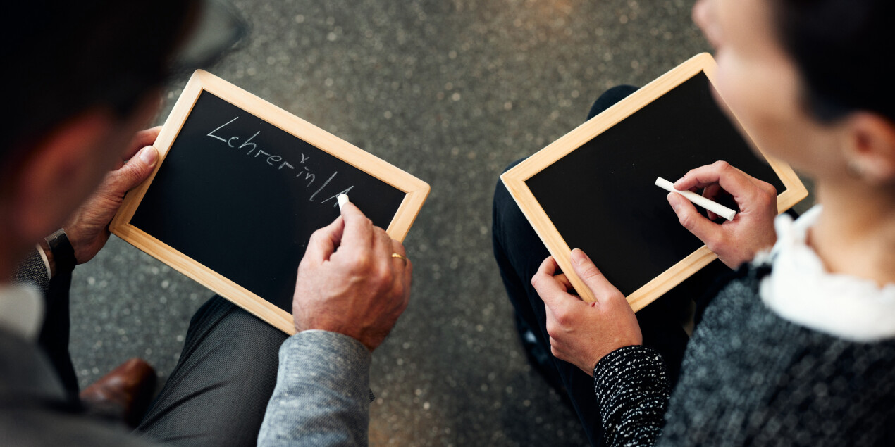 Zwei Personen schreiben mit Kreide auf Tafeln