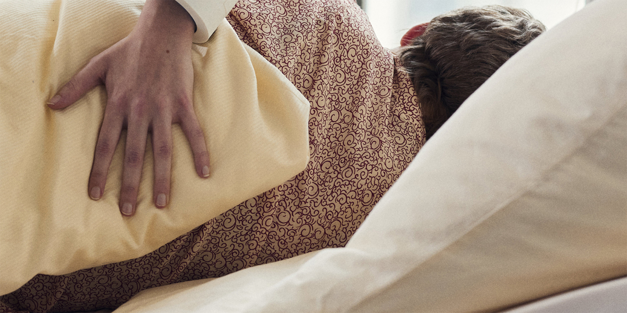 Eine Hand hält eine Frau am Rücken die im Bett liegt