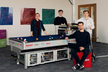 Michael Wilhelmstroop, Antoine Angert, Niklas Hils und Ben Donkervoort  stehen vor dem Billardroboter