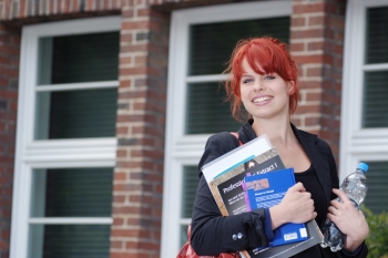 Eine Studentin der FH Bielefeld ist, mit vielen Büchern in der Hand, auf dem Weg zur Vorlesung.