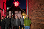 A group of six people in a narrow alleyway between houses, beneath a star illuminated in red