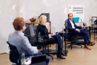 Drei Personen sitzen nebeneinander bei einer Podiumsdiskussion.