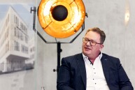 Ein Mann sitzt auf einem Stuhl und guckt schräg nach links.