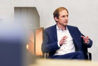 Eine Person sitzt auf einem Stuhl und gestikuliert mit den Händen.