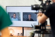 Zwei Personen werden per Videokonferenz-Tool auf einem Bildschirm angezeigt.