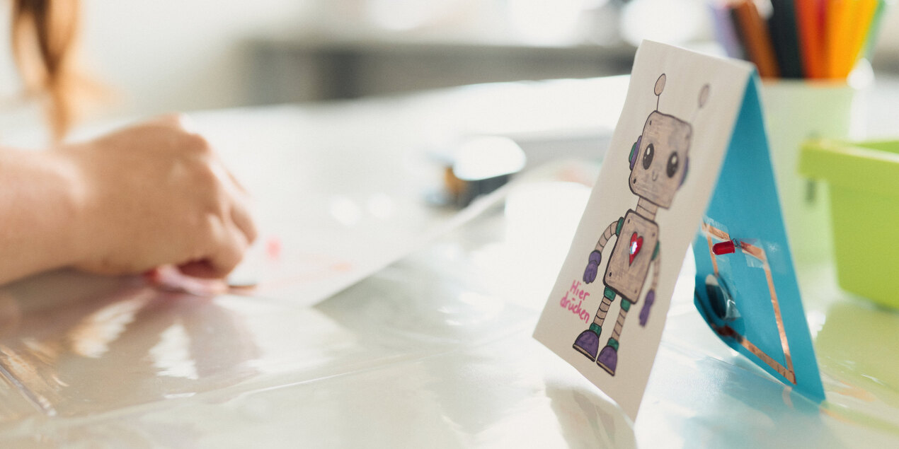 Eine Hand bastelt an einem Papierstromkreis