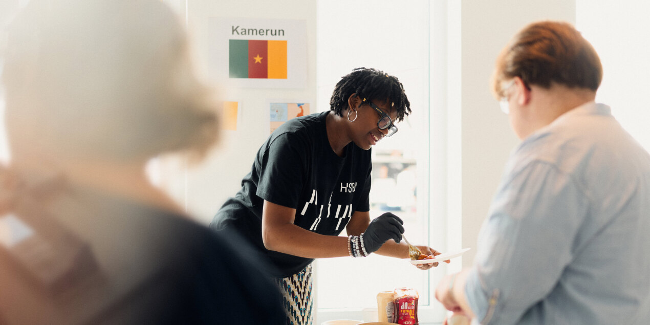 Eine Person füllt Eseen auf und erklärt einer anderen Person das Gericht