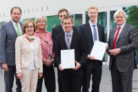 Preisstifter, Hochschulvertreter und Jahrgangsbeste stehen und schauen in die Kamera. Die Jahrgangsbesten halten ihre gerahmte Urkunde in der Hand.