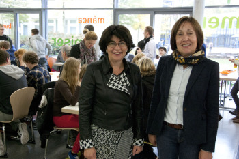 Bürgermeisterin Maria Unger und Fh-Präsidentin Beate Rennen-Allhoff stehen in der mensa des Staädtischen Gymnasiums, hinter ihnen sitzen die Studierenden an Tischen