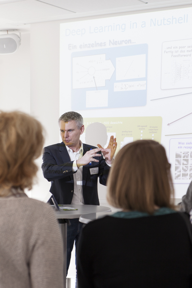 Ein Mann steht vor einer Leinwand mit der Überschrift Deep Learning