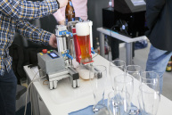 Auf einem Tisch steht eine Maschine mit einem gefüllten Weizenbierglas