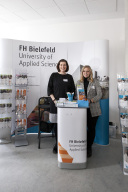 Zwei Frauen stehen vor einem Aufsteller mit dem Schriftzug der FH Bielefeld