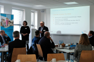 Ein Mann und eine Frau stehen vor einer Gruppe Menschen