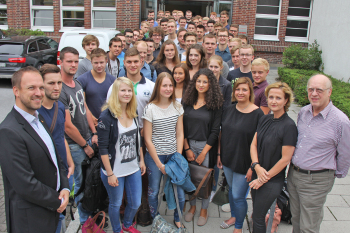 Die Erstsemester stehen mit den Dozenten vor dem Eingang zum Flöttmanngebäude, in dem die Räume der FH Bielefeld in Gütersloh untergebracht sind.