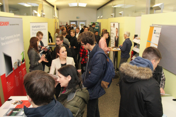 Viele Menschen stehen im geräumigen Flur des Studienortes und unterhalten sich.