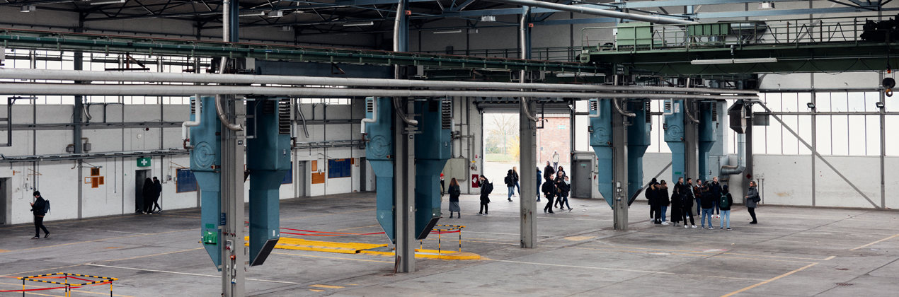 Personen stehen in einer leeren Lagerhalle