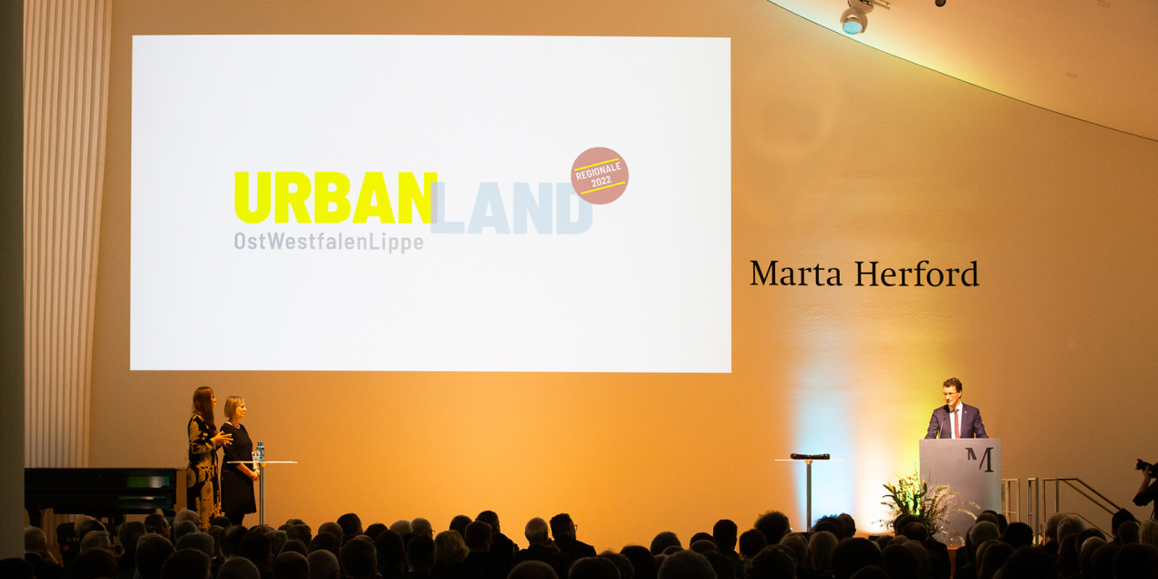 Hendrik Wüst steht auf einer Bühne hinter einem Redepult vor Publikum