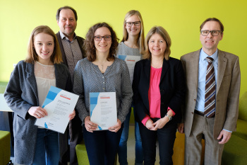 Sechs Personen stehen nebeneinander. Drei weibliche Personen halten Zertifikate in den Händen.