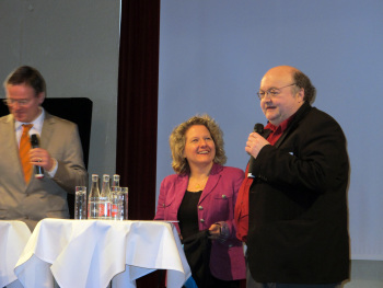 Professor Bahndorf am Mikrofon, Ministerin Schulze hört zu