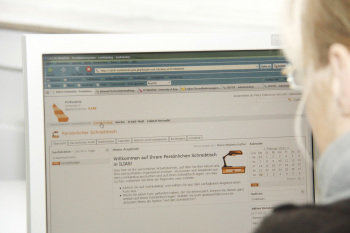 Eine Frau sitzt vor dem Computerbildschirm und öffnet in ILIAS die Seite \