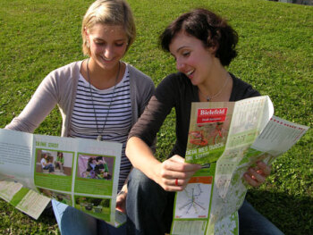 Tipps rund ums Studentenleben: Birte Schwerte und Johanna Leuner (v. l.) vom Wissenschaftsbüro der Bielefeld Marketing GmbH testen den neuen Studi Kompass.