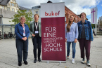 Vier Frauen stehen neben einem Aussteller mit der Aufschrift bukof Für eine geschlechtergerechte Hochschule