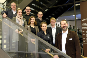 Gruppenfoto mit acht Personen auf einer Treppe.