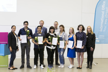 Zehn Personen stehen nebeneinander und blicken in die Kamera.