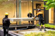 Drei Männer befestigen eine Betonplatte in dem Innenhof, in dem das Kunstwerk von Hans Uhlmann positioniert wird