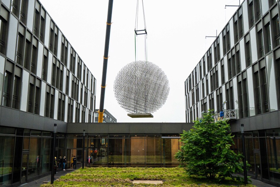 Das kugelförmige Kunstwerk ist am Kran befestigt und wird in den Innenhof angeliefert