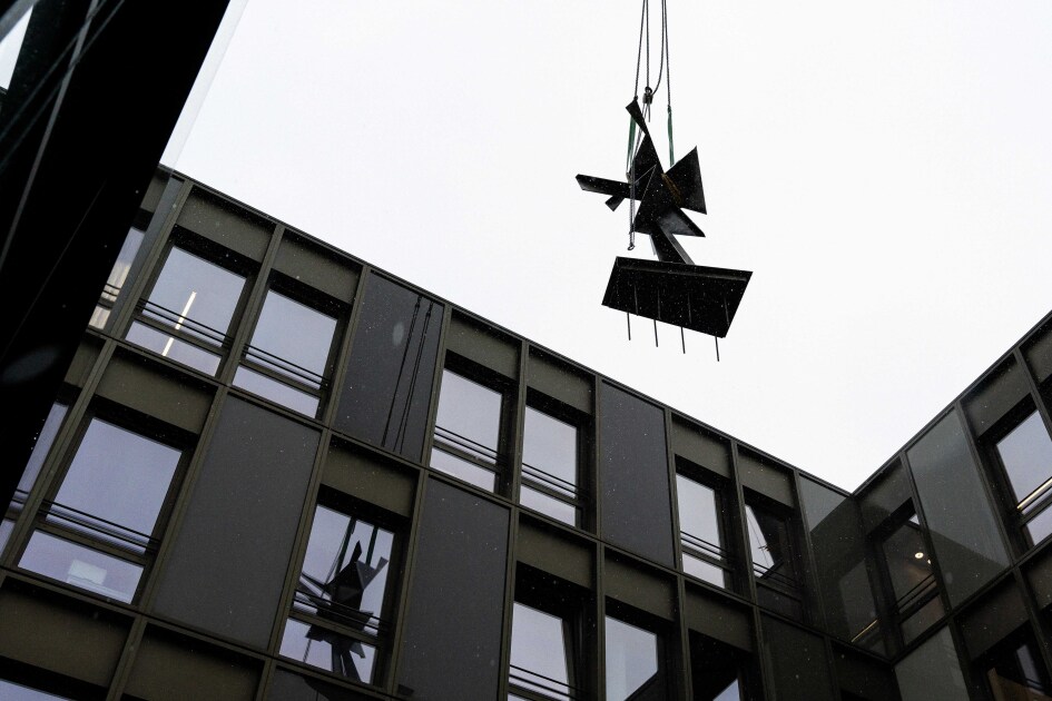 Die Skulptur von Hans Uhlmann hängt an einem Kran und wird zwischen den Gebäudeteilen in den Innenhog angeliefert