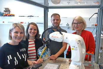 Vier Personen stehen um einen Kuka-Industrieroboter