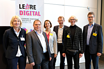 Sechs Personen stehen nebeneinander und blicken in die Kamera.