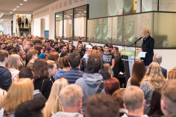 Eine Person am Rednerpult vor dem Publikum
