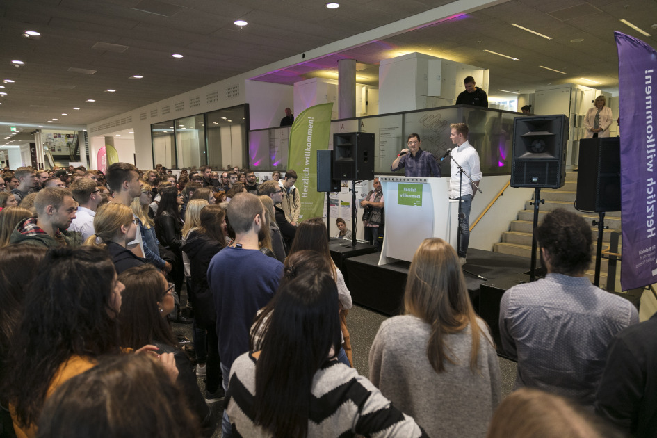 Zwei Männer stehen für einer Gruppe von Menschen und informieren.