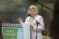 Eine Frau steht vor einem Mikrophon an einem Rednerpult