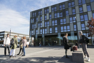 zwei Männer und drei Frauen stehen vor dem Gebäude der FH im Sonnenschein