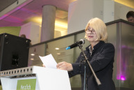 Eine Frau steht vor einem Mikrophon an einem Rednerpult