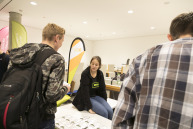 Eine Frau sitzt auf einer Tischkante ein Mann spricht mit ihr