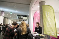 Ein Frau zeigt einer anderen Frau etwas eine dritte Frau schaut zu