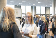 Eine Frau reicht einer anderen Frau einen Flyer