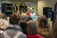 Vor einer Menschenmenge steht eine Frau an einem Rednerpult