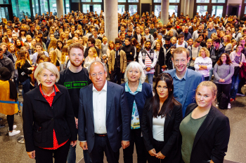 Sieben Personen stehen nebeneinander und blicken in die Kamera.