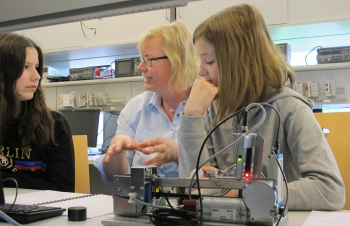 Drei Personen sitzen nebeneinander und arbeiten an einem Gerät