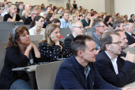 Blick im Audimax auf mit Menschen gefüllte Reihen.