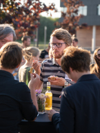 mehrere Personen stehen um einen Stehtisch und Essen